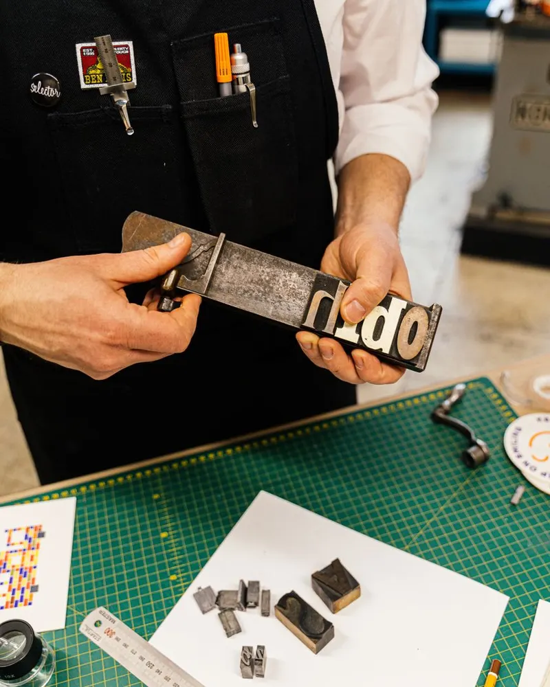 Mains tenant des caractères typographiques dans un atelier